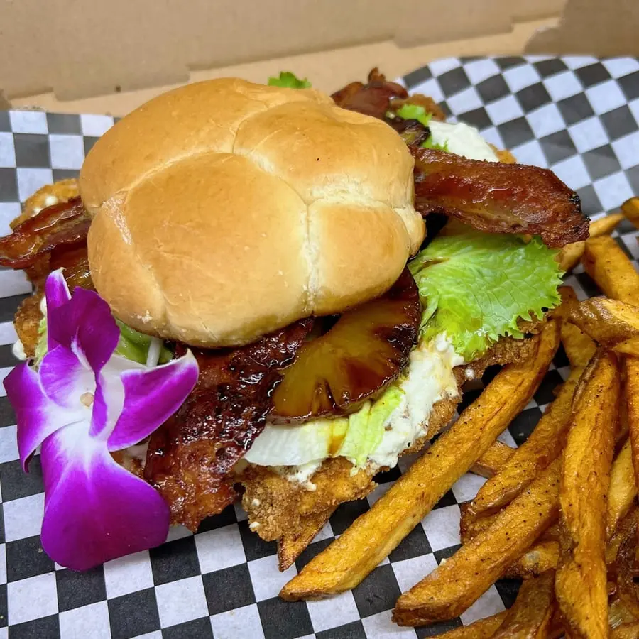 The Alohog sandwich with grilled pineapple, bacon and fries on checkered paper